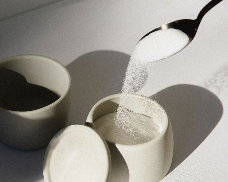 Sugar - spoon pouring sugar over small jar